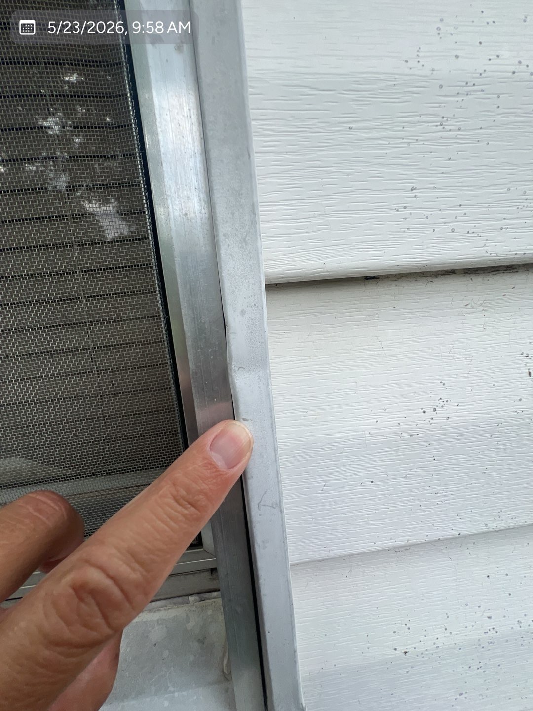 Hail impact damage on metal trim beside a residential window